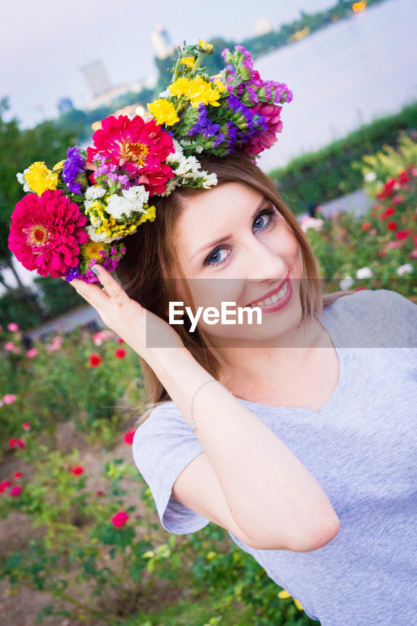 PORTRAIT OF SMILING WOMAN WITH FLOWERS