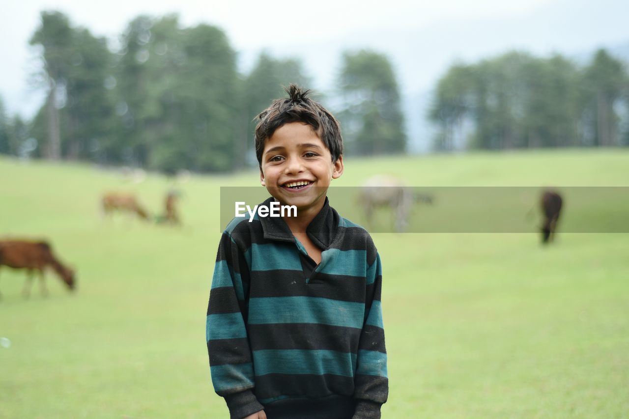 PORTRAIT OF SMILING MAN STANDING ON FIELD