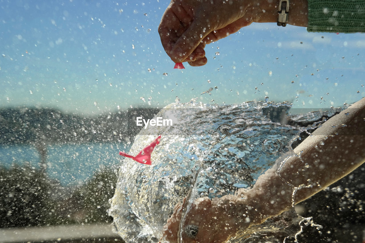 Cropped hands of woman exploding water bomb outdoors