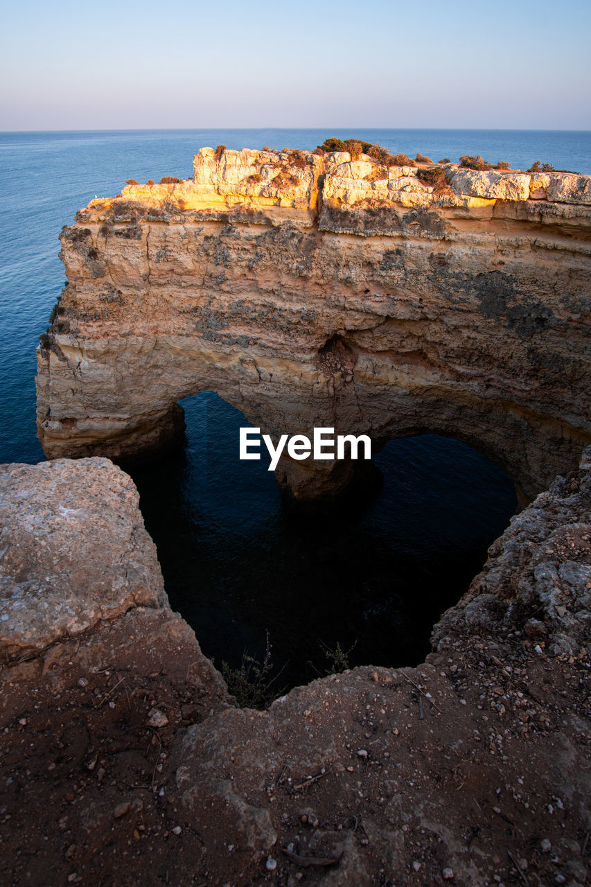 ROCK FORMATION ON SEA SHORE AGAINST SKY