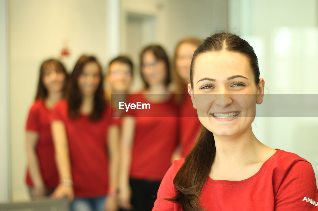 Portrait of smiling young woman against friends