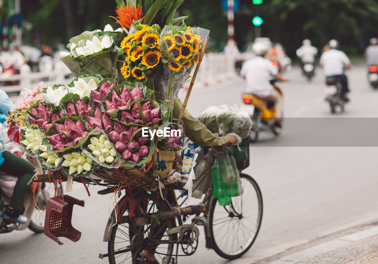Rear view of man selling bouquets on bicycle at street 