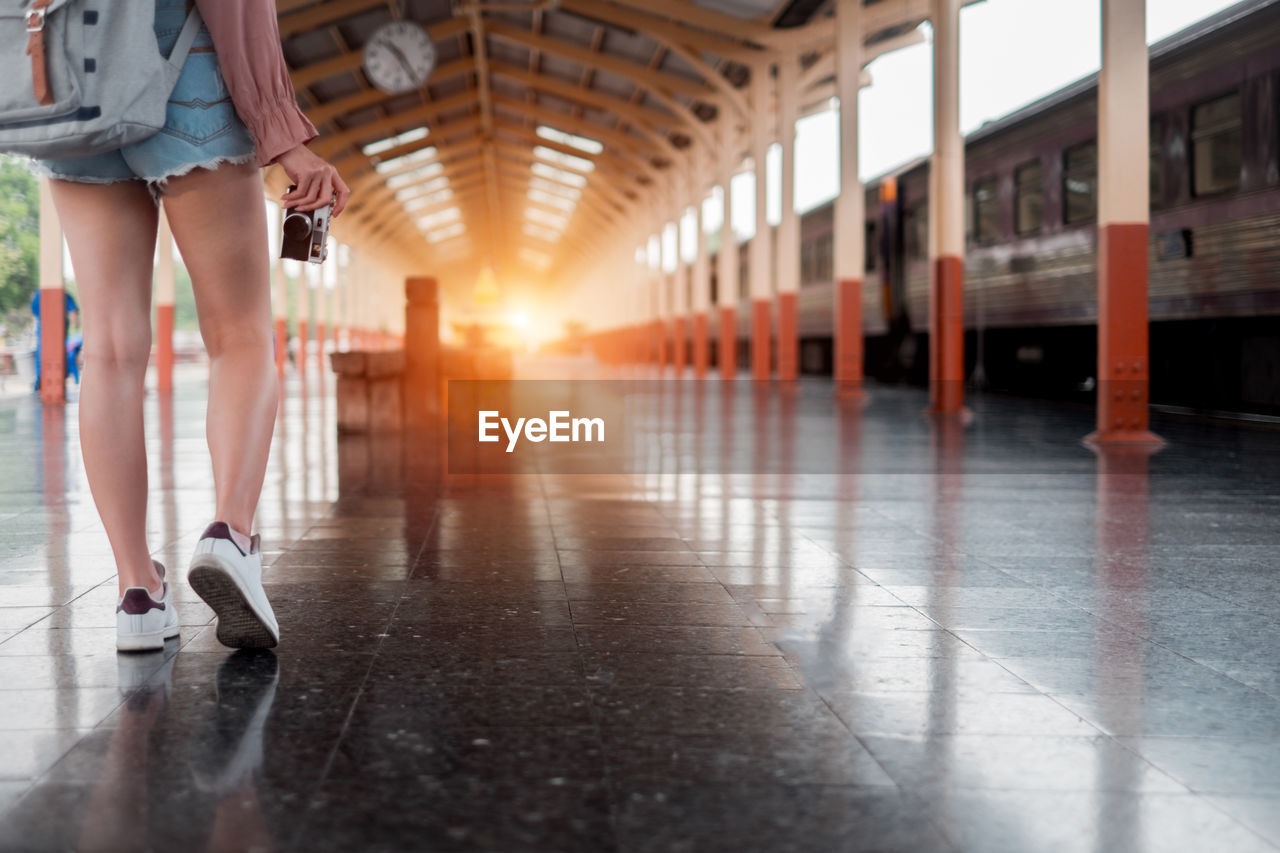 Low section of woman walking on railroad station platform