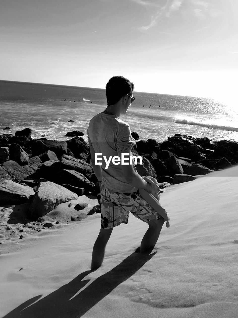 MAN STANDING ON ROCK AT BEACH