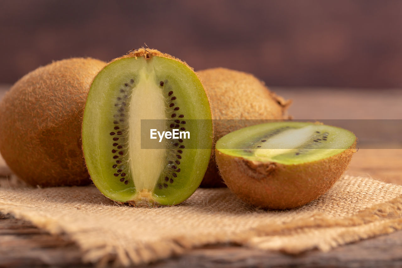 Half of the kiwi slice placed on the brown sack on the wooden table