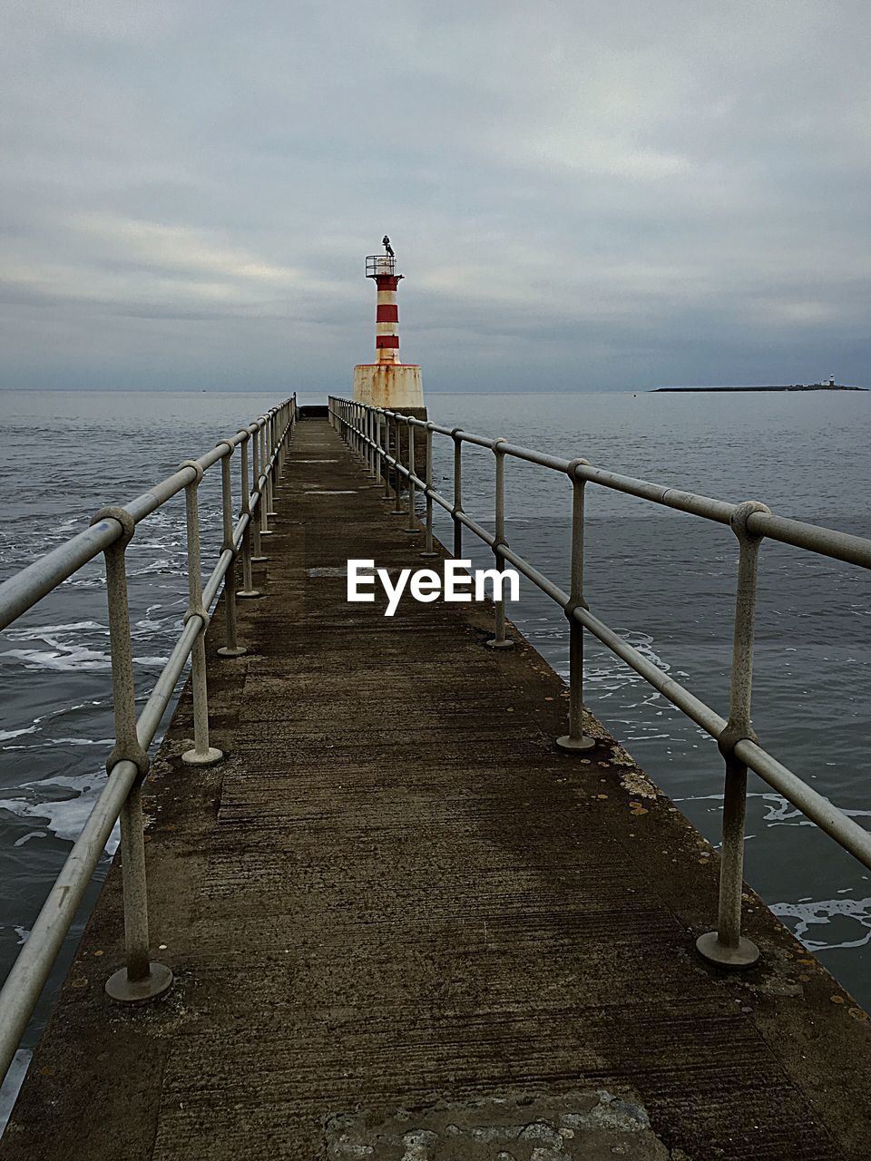 PIER LEADING TOWARDS LIGHTHOUSE AT SEA AGAINST SKY