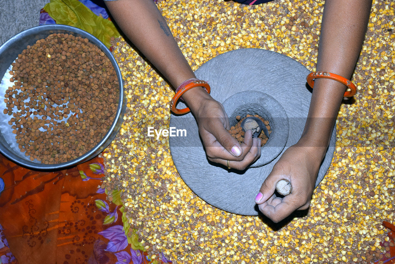 A village woman's hand, grinds gram in an old hand operated flour mill.