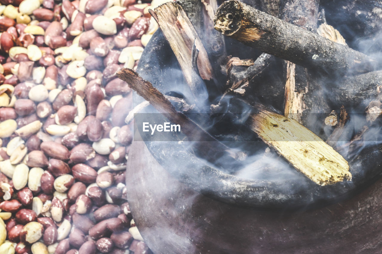 High angle view of smoke from woods in container over peanuts