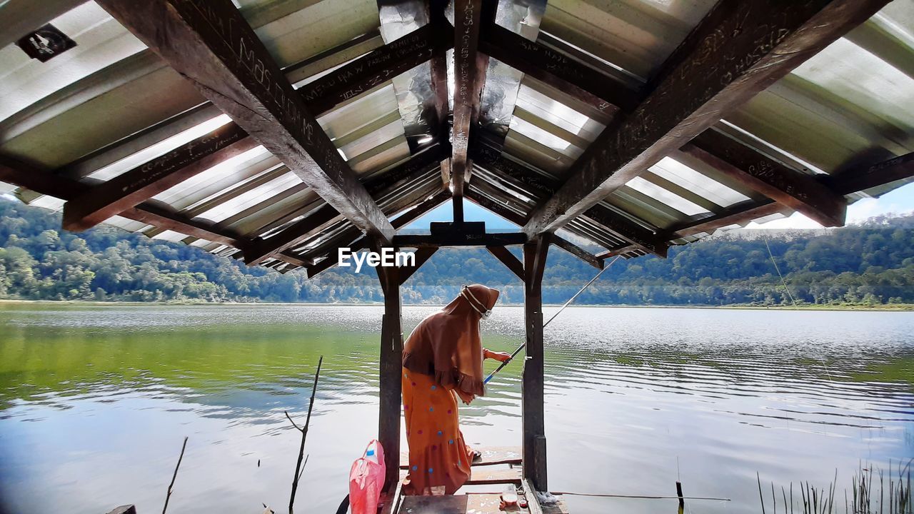 rear view of young woman standing in boat in lake