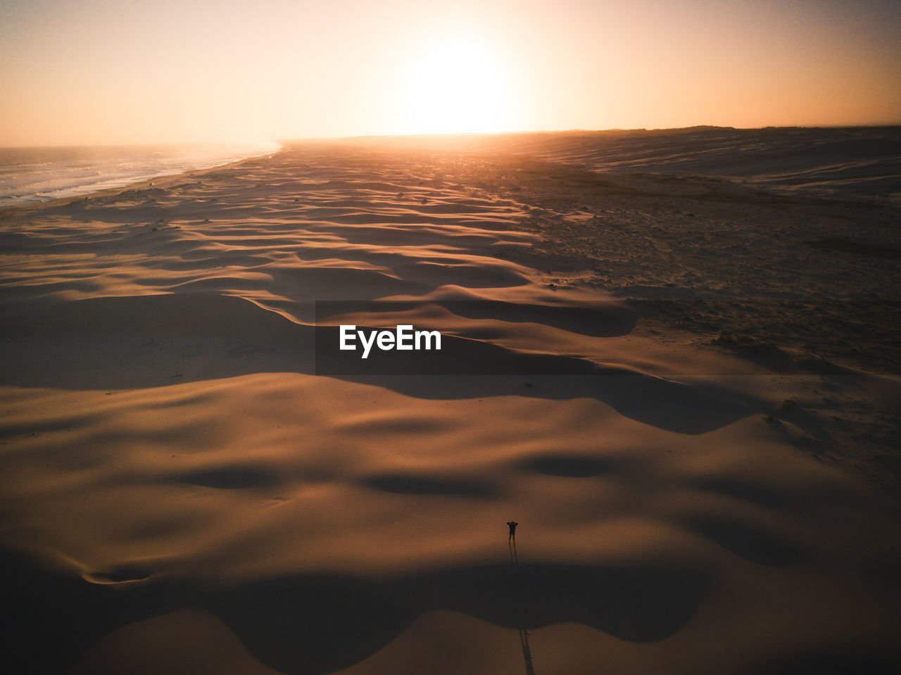 Scenic view of beach against clear sky during sunset