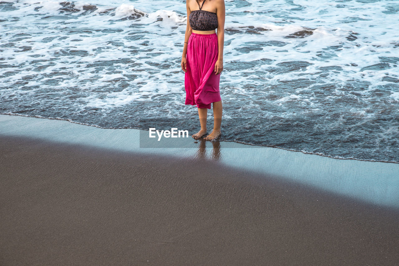 Low section of woman standing on beach