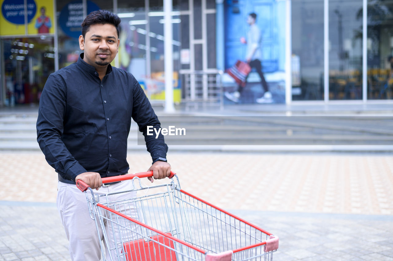 PORTRAIT OF SMILING YOUNG MAN ON STORE