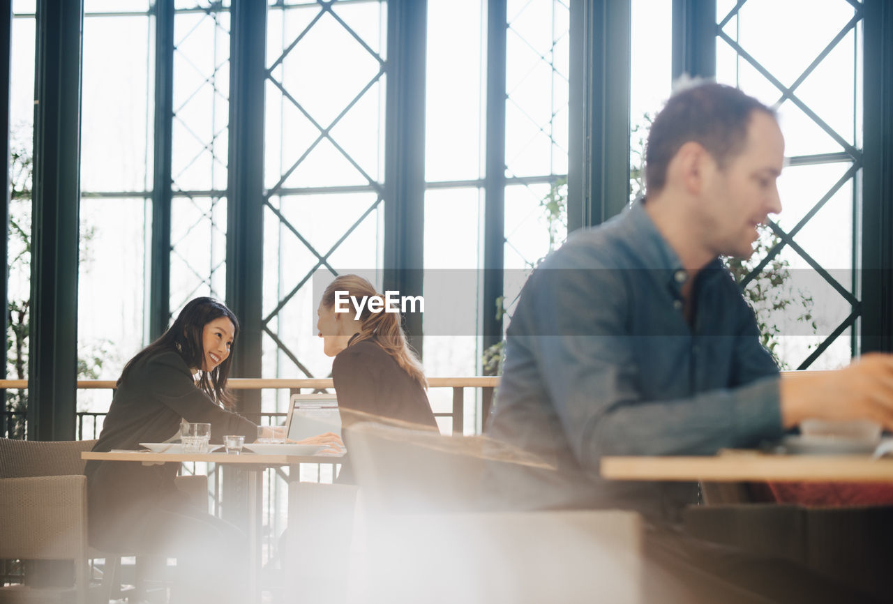 Smiling businesswomen sitting at table during meeting in office cafeteria