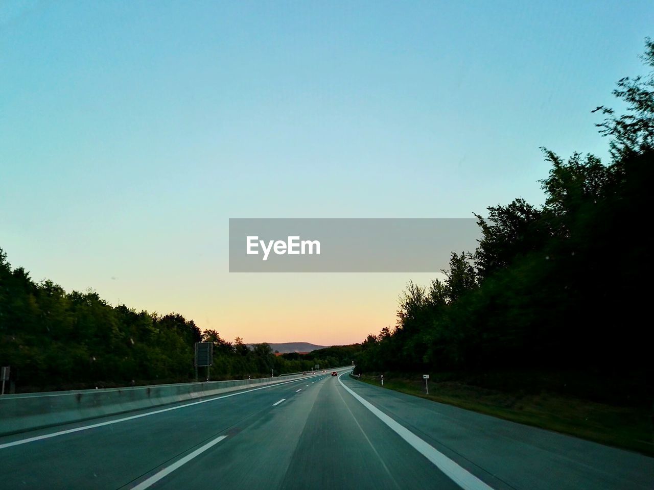 VIEW OF COUNTRY ROAD AGAINST BLUE SKY