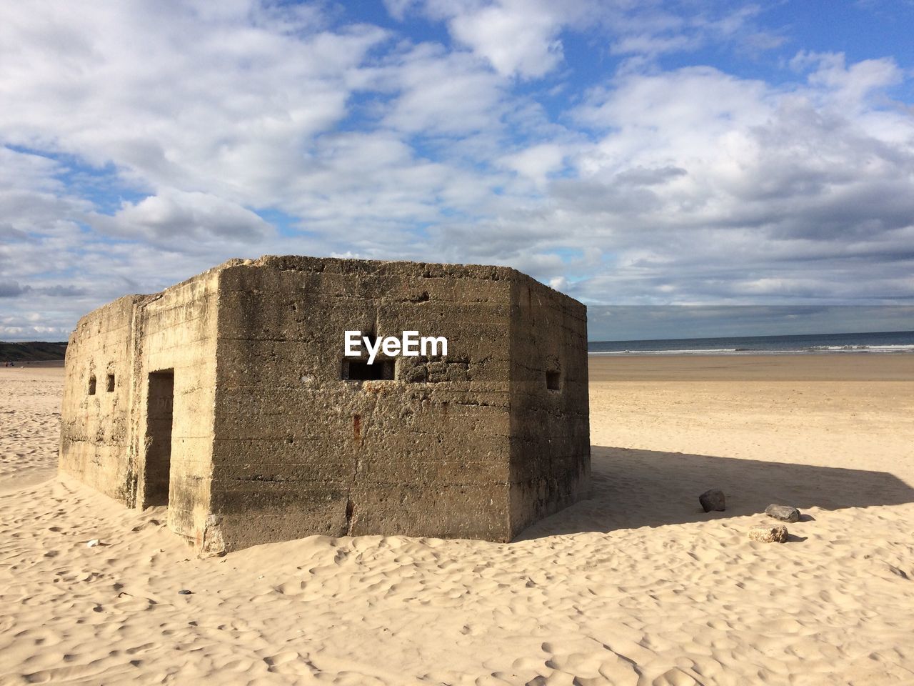 Built structure on sandy beach against cloudy sky
