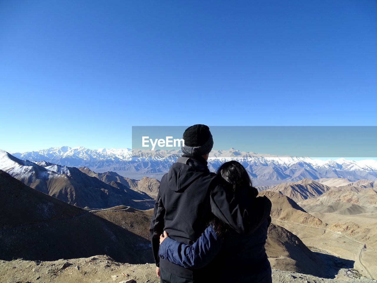 Rear view of people looking at mountain against sky