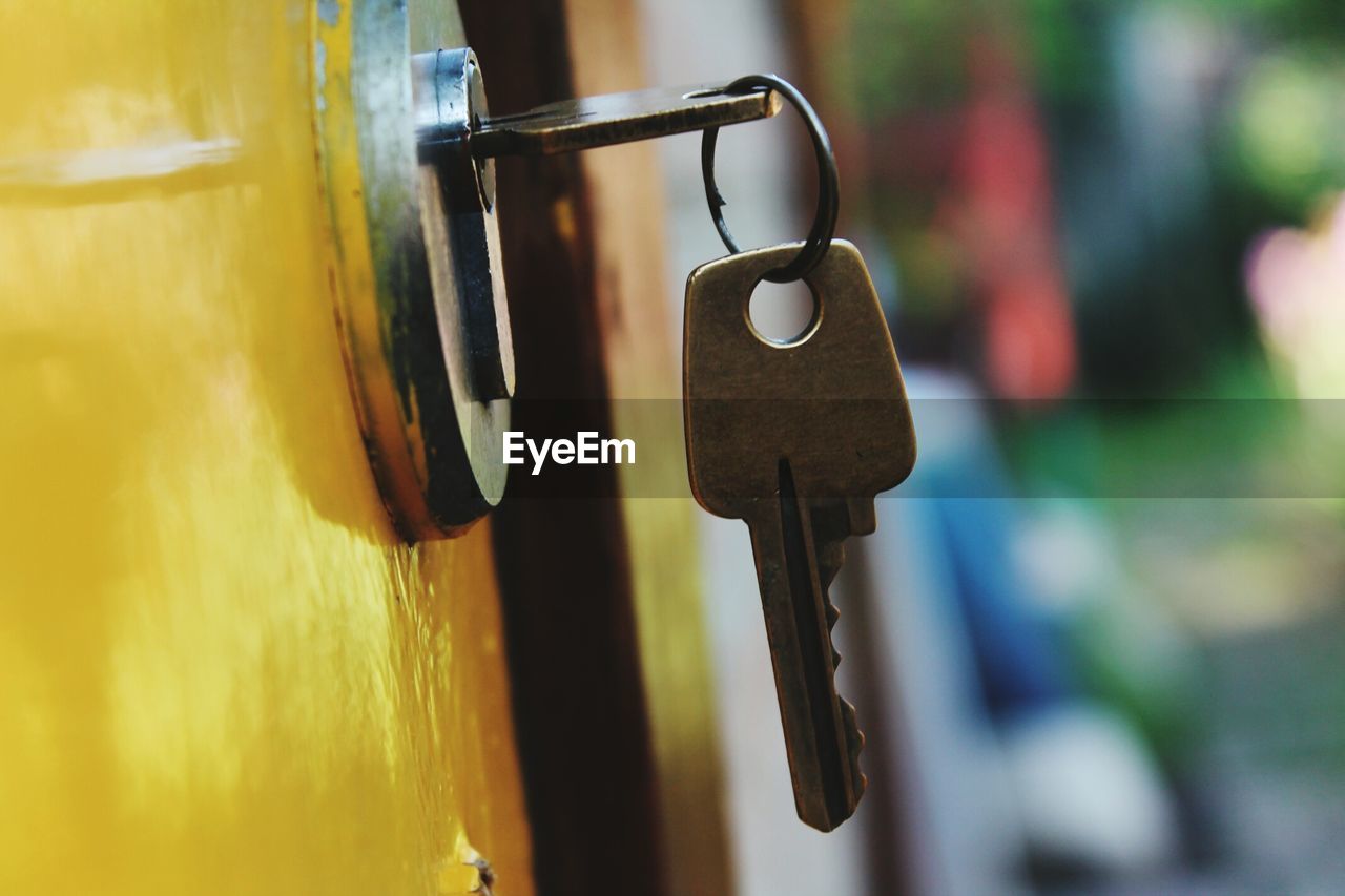 Close-up of keys in hole on yellow door