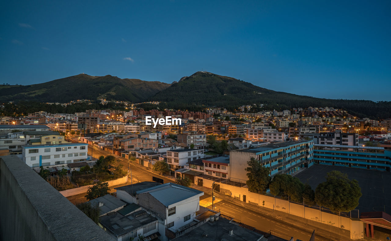 Illuminated cityscape against clear blue sky at night