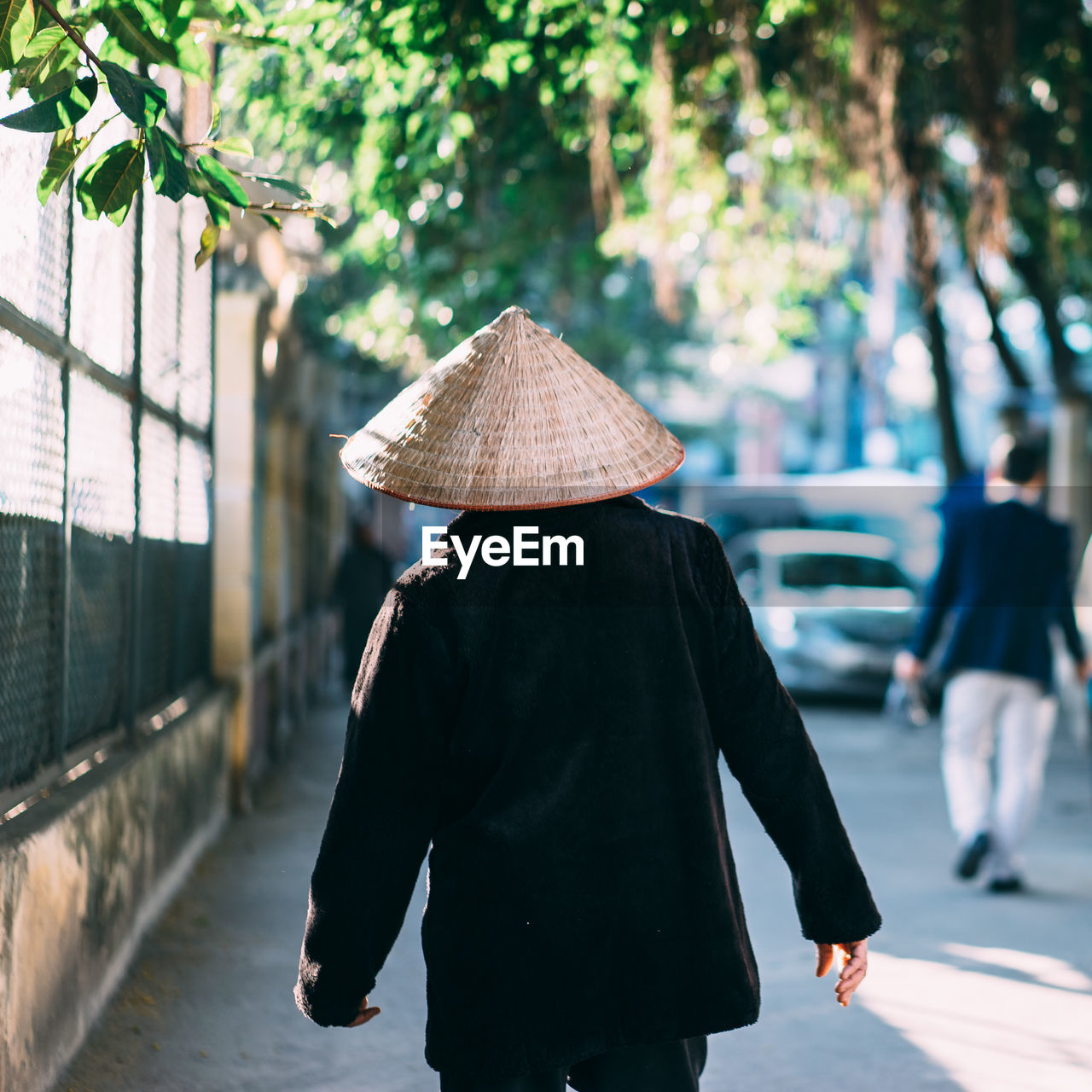 Rear view of man wearing hat while walking on road