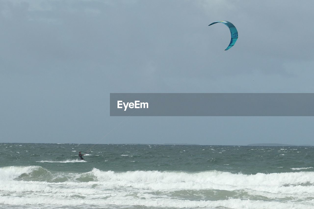 Wind surfing in sea  with horse riding on beach 