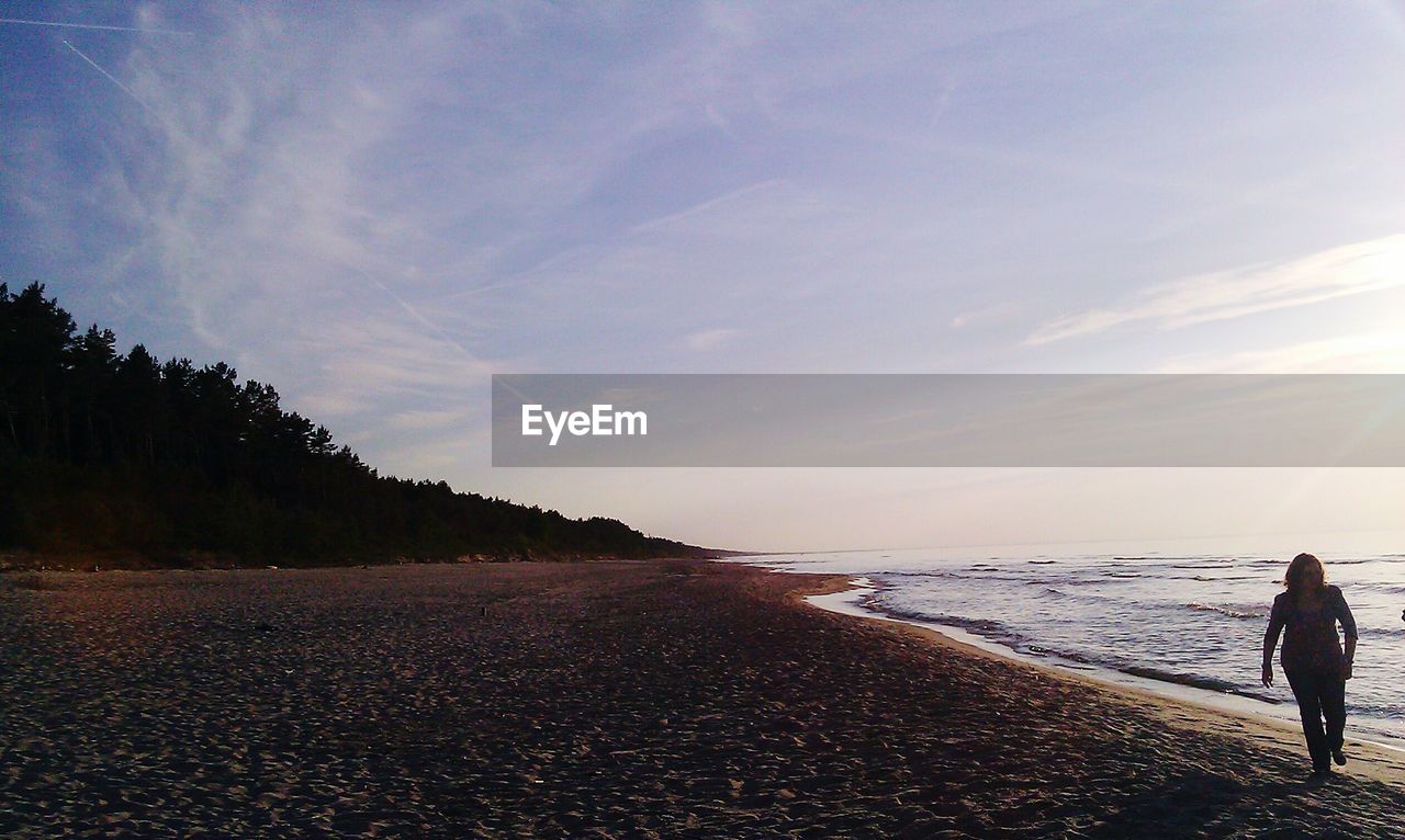 Silhouette of woman walking along beach