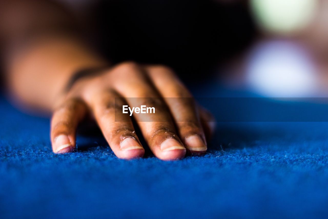 Close-up of human hand on carpet