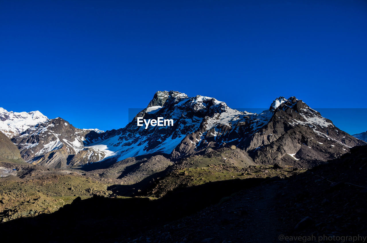 Scenic view of snowcapped mountains against clear blue sky