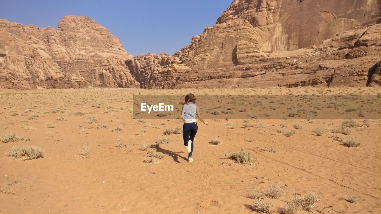 Full length rear view of woman running in the desert