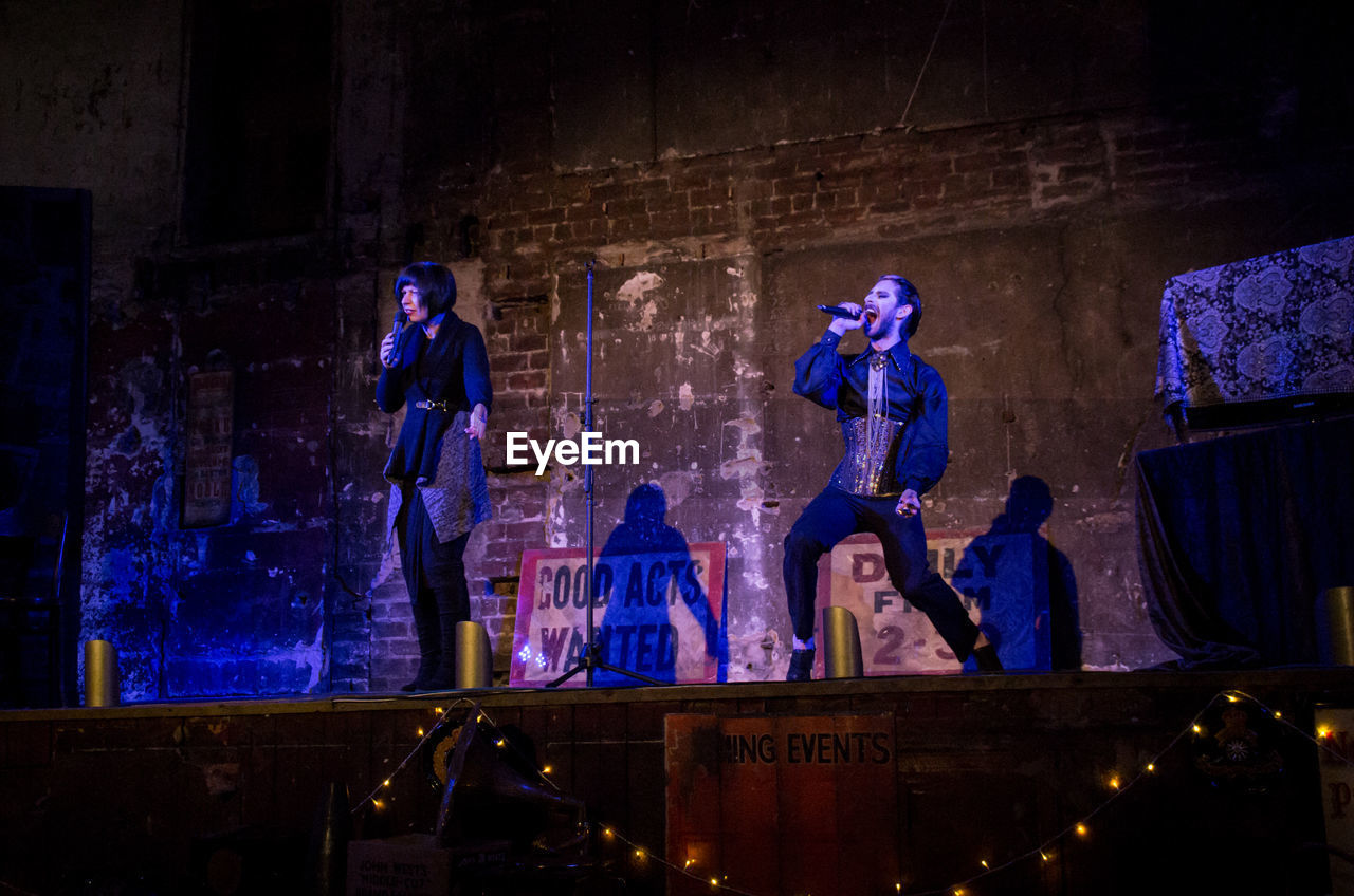 MEN STANDING IN ILLUMINATED STAGE