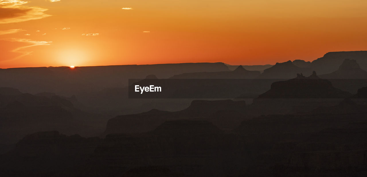 Scenic view of silhouette mountains against orange sky