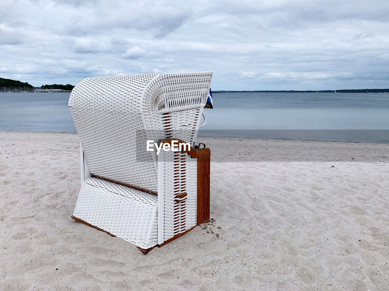 Hooded chairs on sand at beach against sky