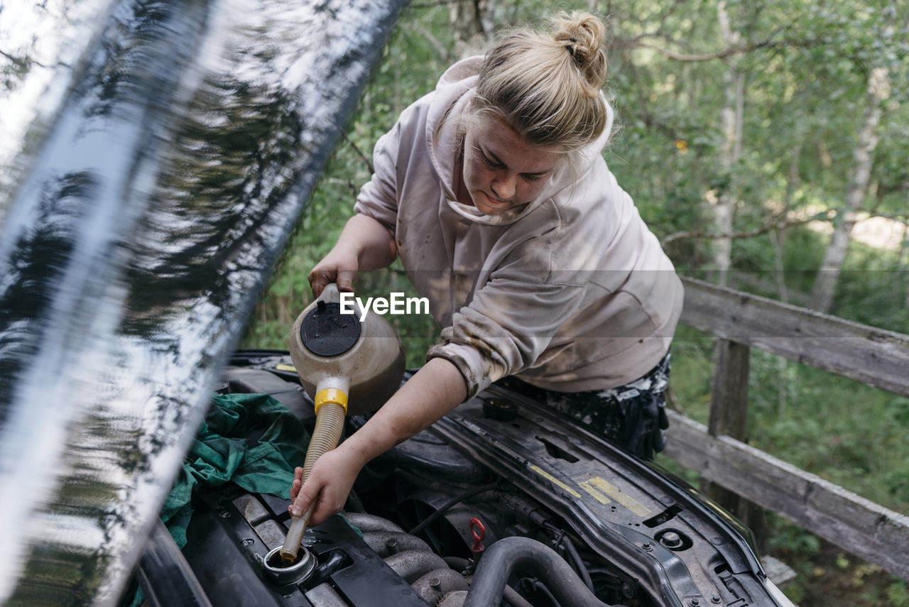 Woman pouring oil into engine