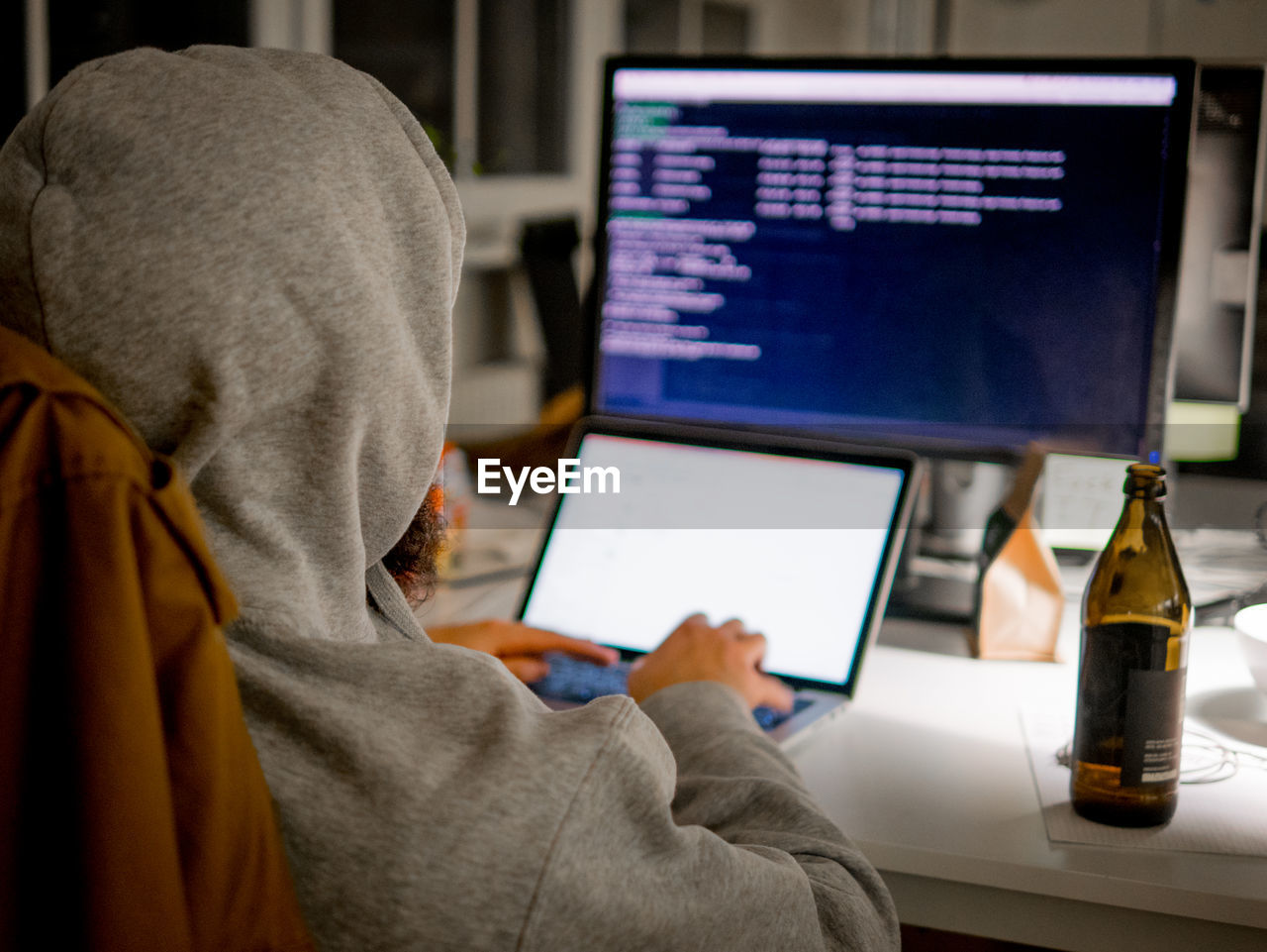 Rear view of person using computer in office