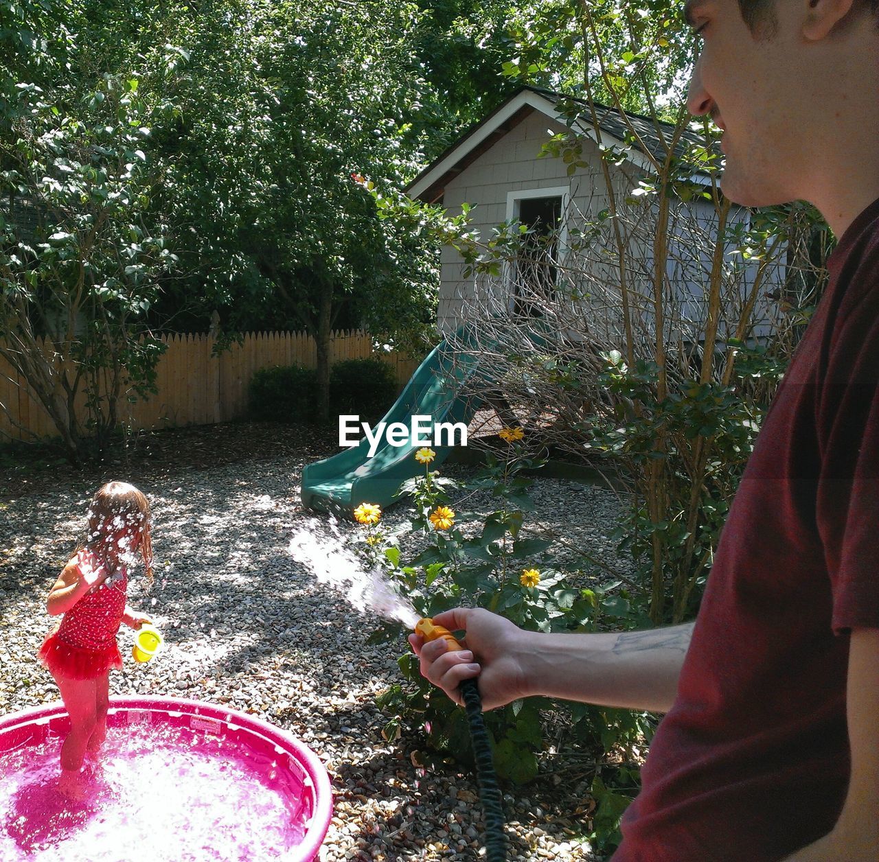 Smiling man spraying water on girl at lawn