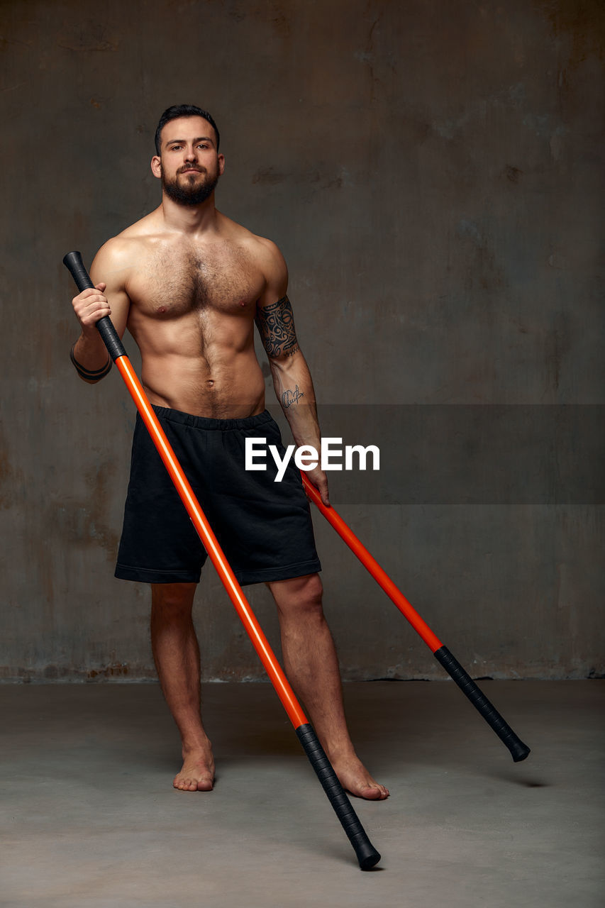 Portrait of men holding combat stick in gym