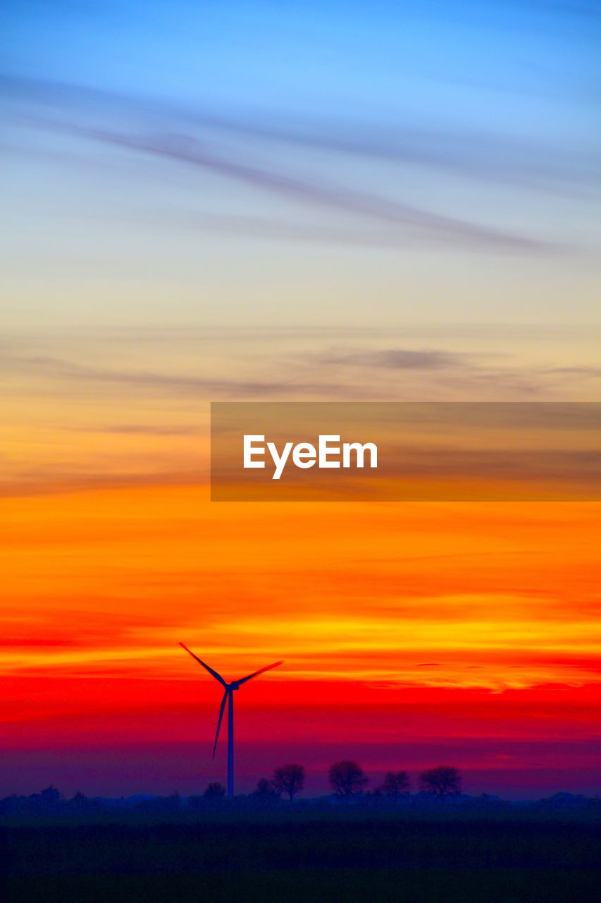 SILHOUETTE WIND TURBINE AGAINST ORANGE SKY