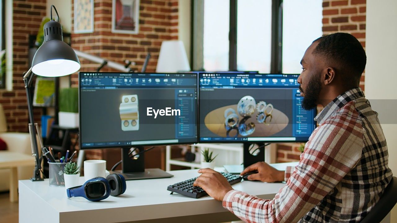 rear view of man using digital tablet while standing in office