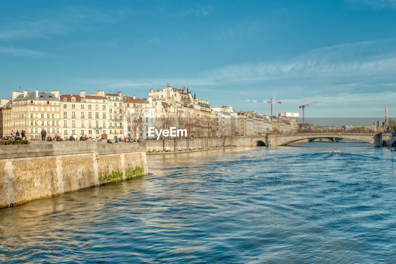 View of buildings by sea against blue sky