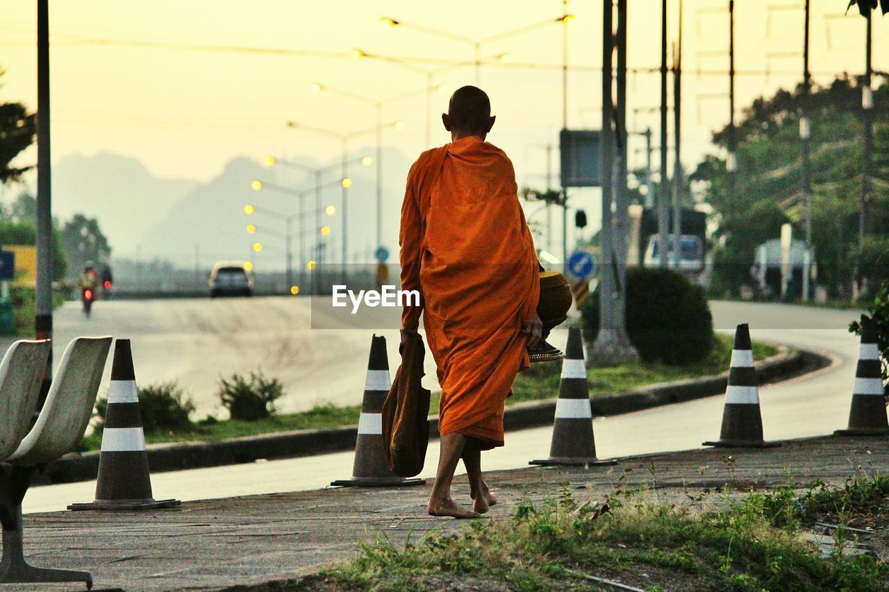 Rear view of monk walking on sidewalk