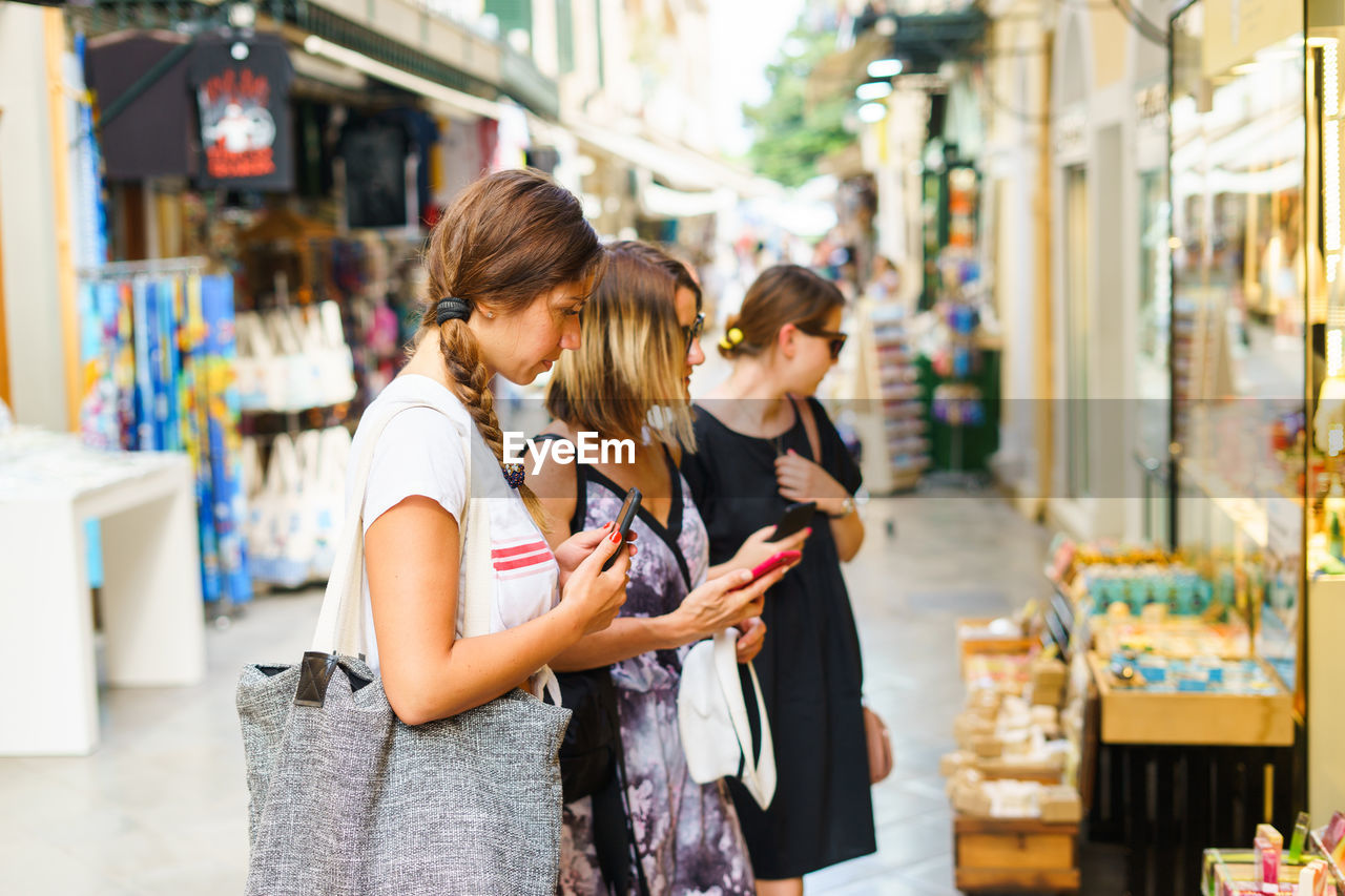 Friends holding mobile phones standing at market