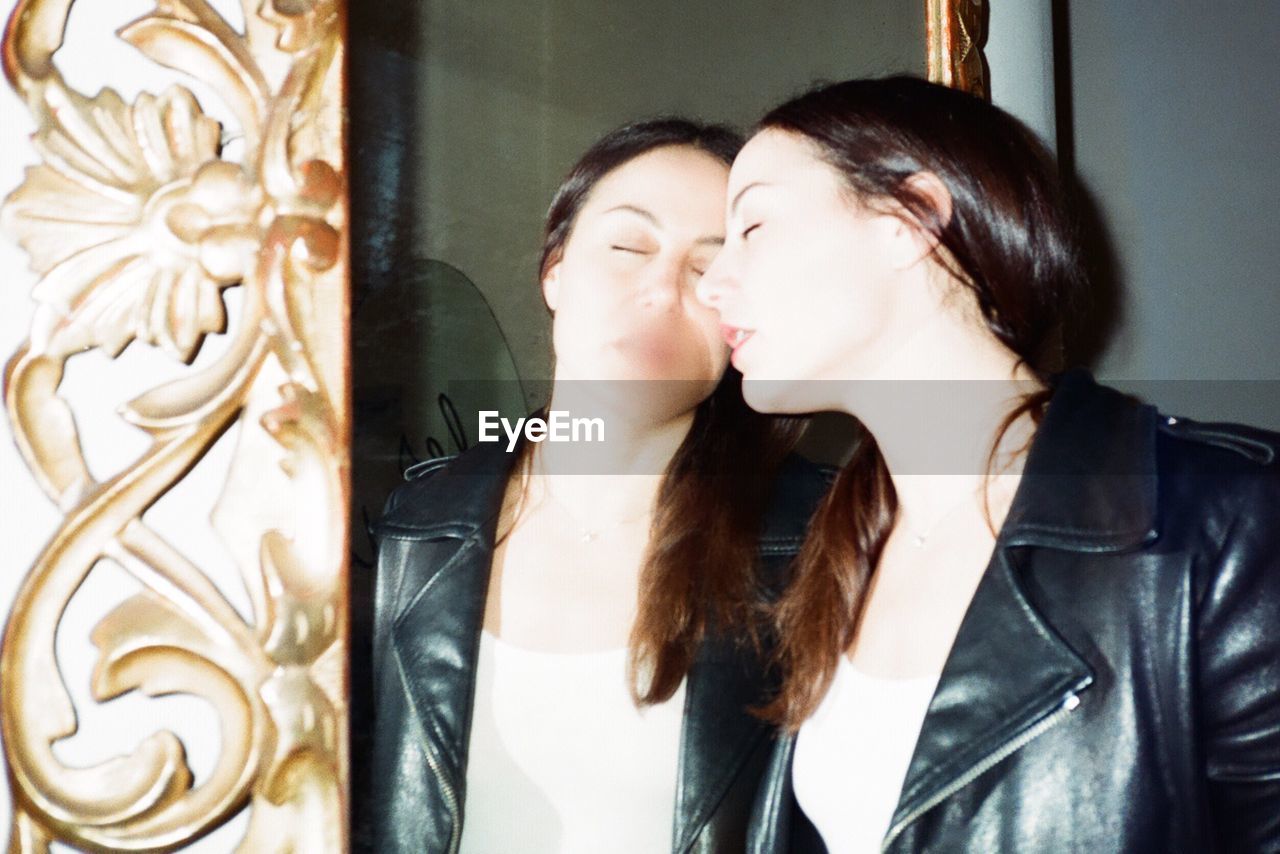 Woman with closed eyes leaning on mirror at home