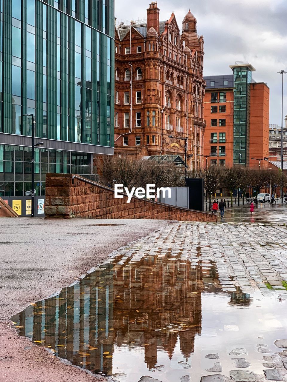 REFLECTION OF BUILDINGS IN PUDDLE ON STREET IN WINTER