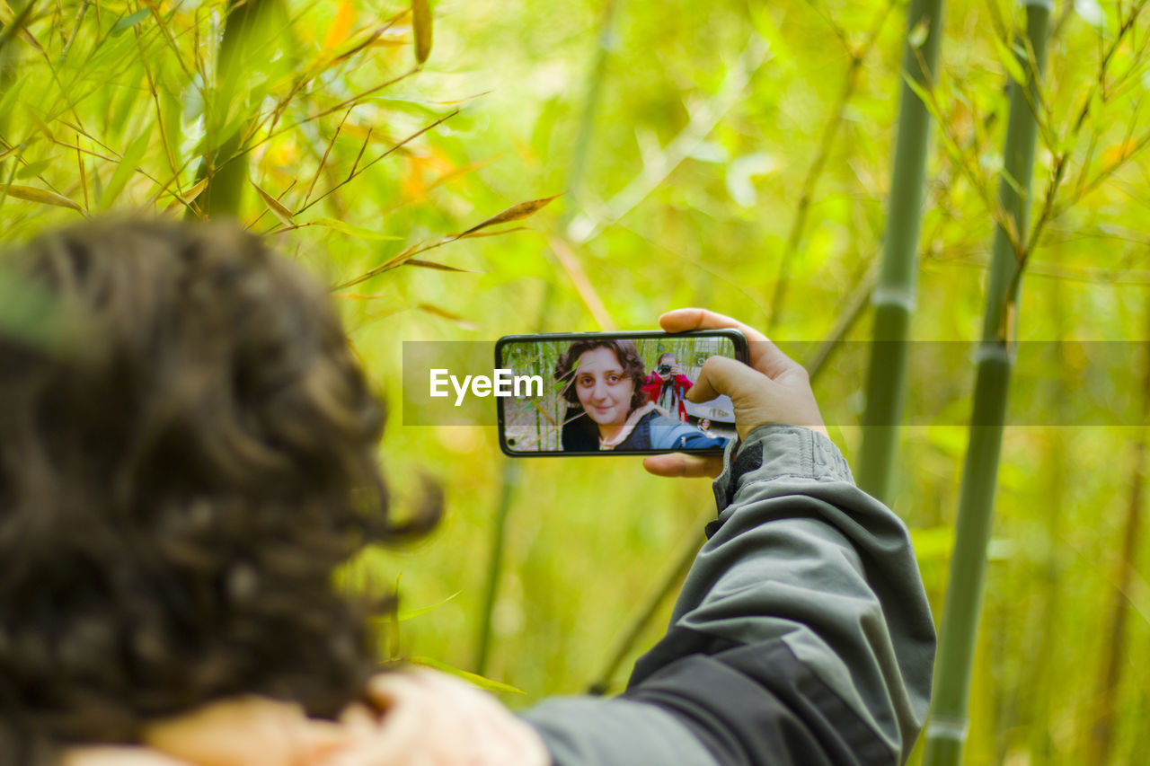 Woman takes self photo, mobile phone and nature background