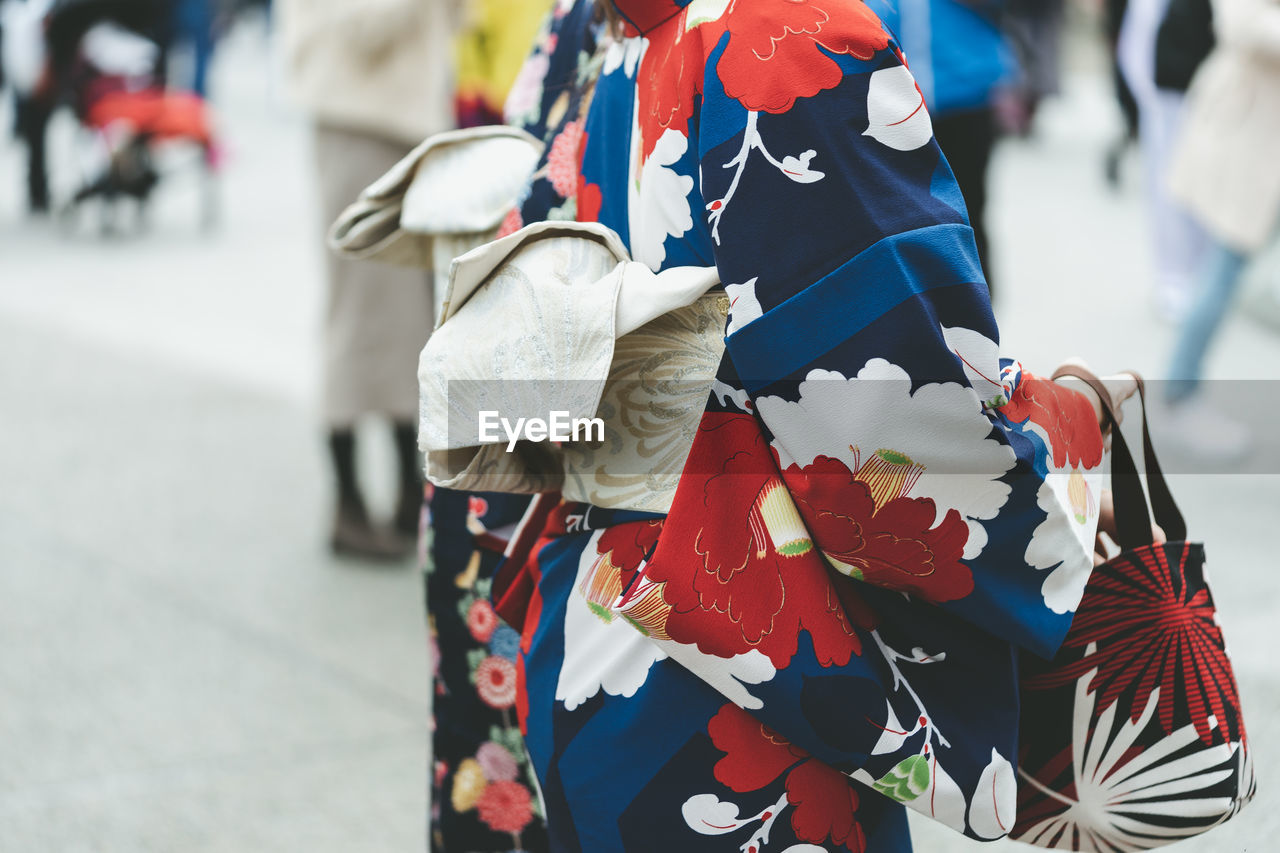 Midsection of woman in kimono standing on street