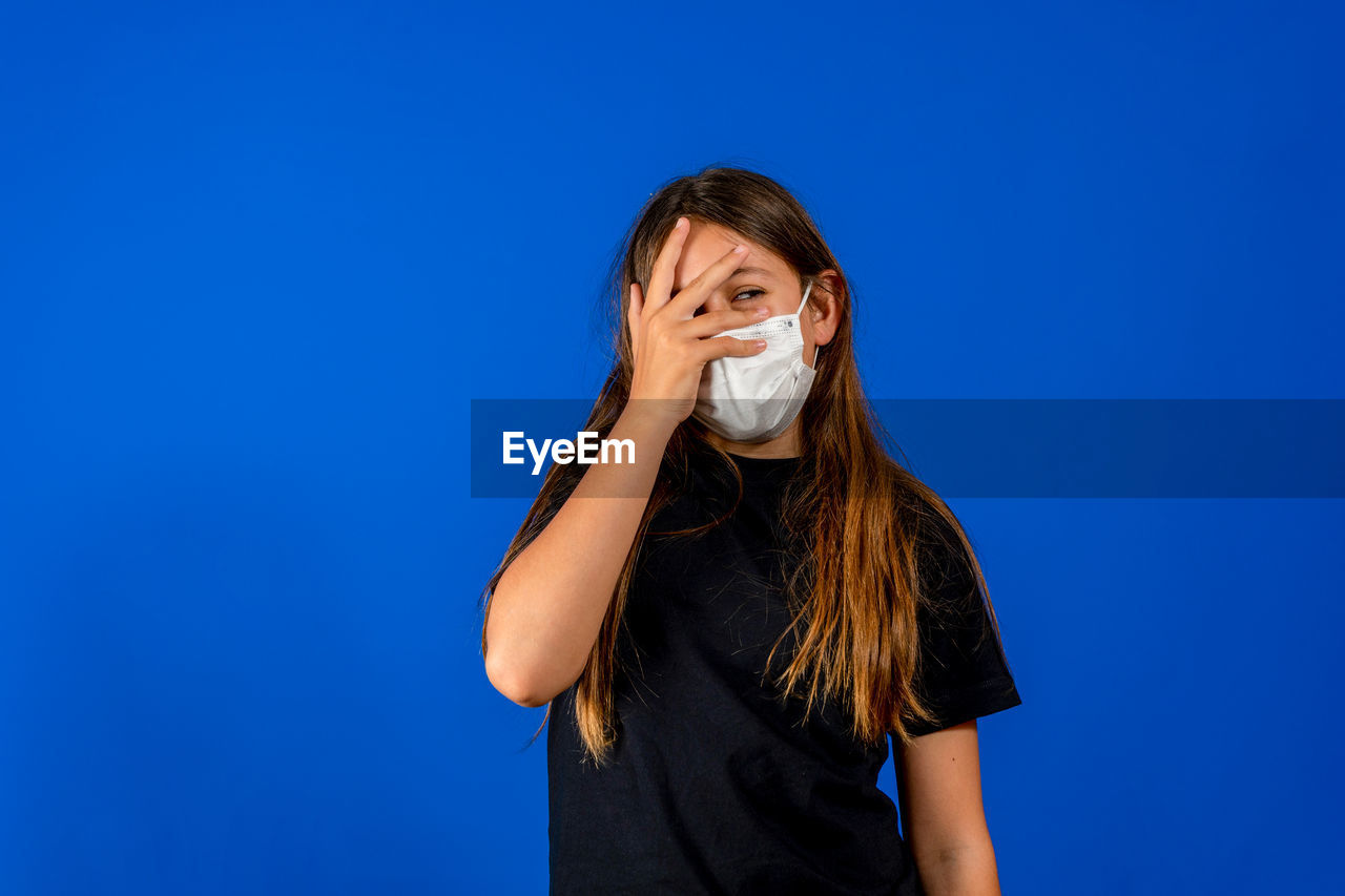 MIDSECTION OF WOMAN HOLDING BLUE AGAINST WHITE BACKGROUND