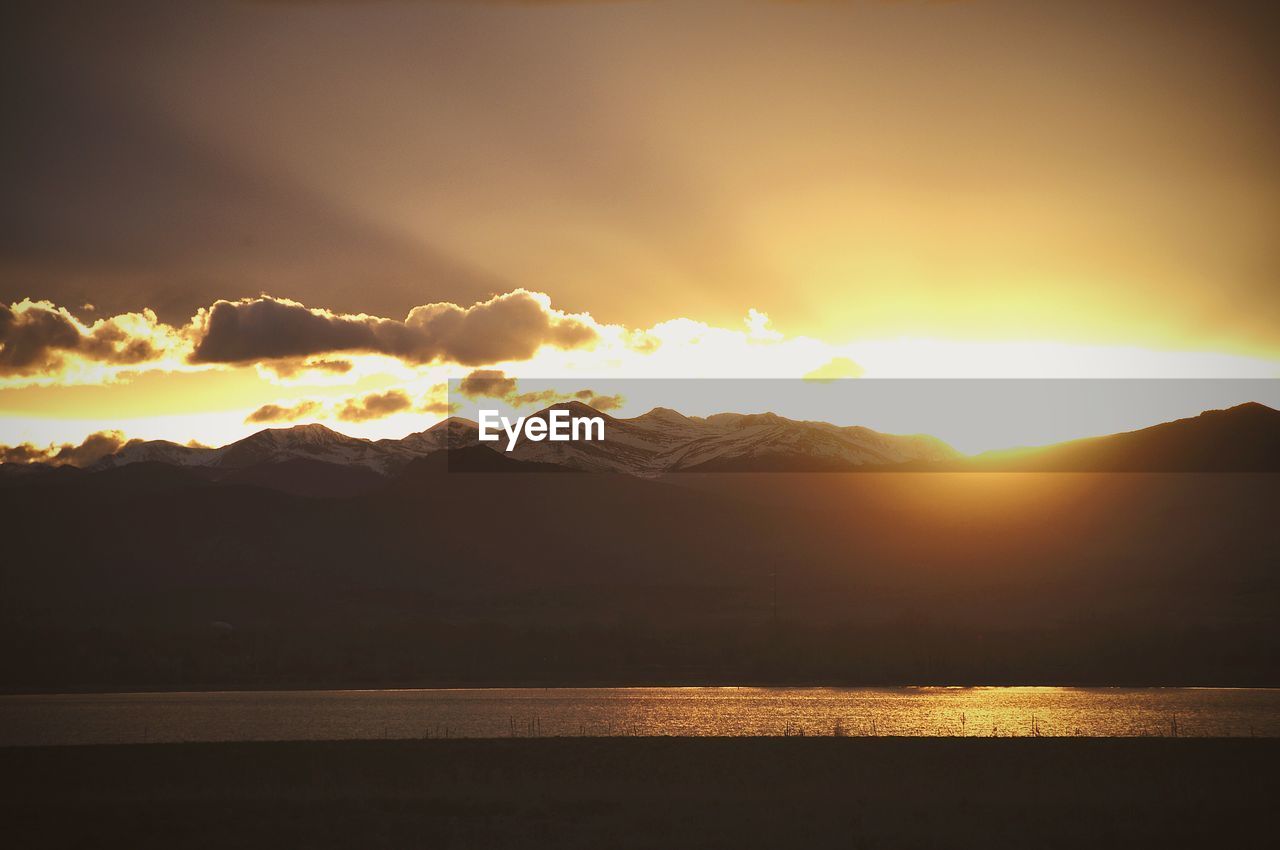 SUN SHINING THROUGH CLOUDS OVER MOUNTAINS