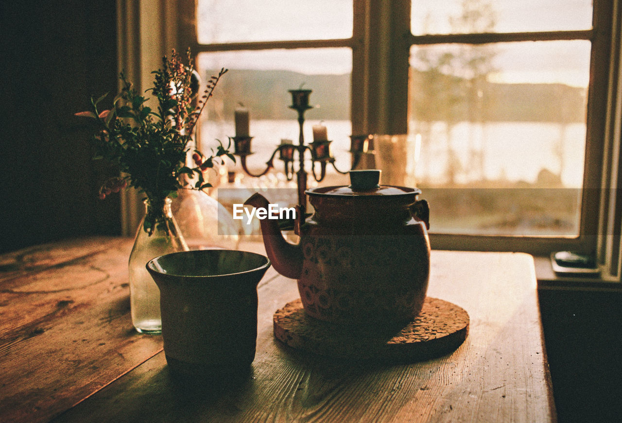 Close-up of tea cup on wooden table against window at home