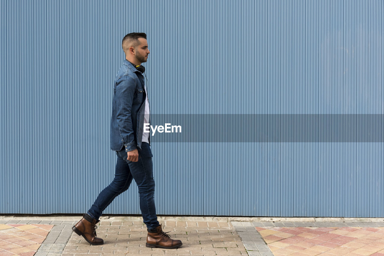 Portrait of a young man walking over blue background