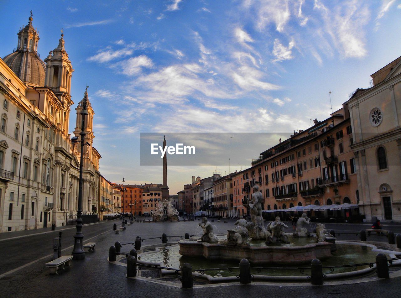 Sculptures in fountain amidst buildings against sky at piazza navona