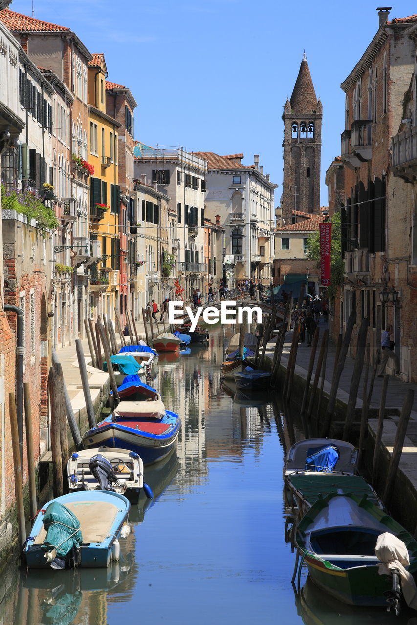 Boats moored on canal amidst buildings in city